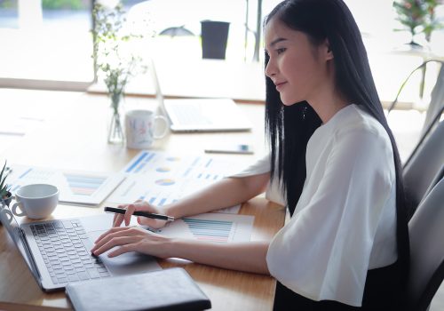 Asian business woman working in in coffee shop cafe with laptop paper work  (Business woman concept.)